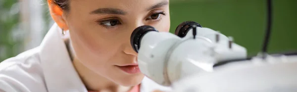 Молодий окуліст, який працює з офтальмоскопом на розмитому передньому плані, банер — стокове фото