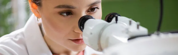 Young oculist working with ophthalmoscope on blurred foreground, banner — стоковое фото
