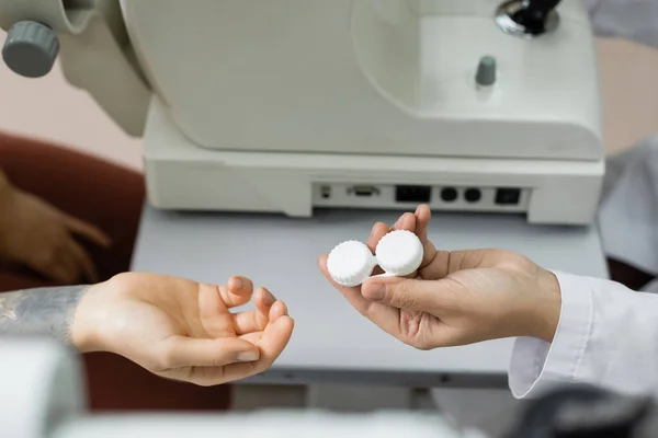 Vue recadrée de l'oculiste donnant cas de lentille au patient écran de vision rapprochée — Photo de stock