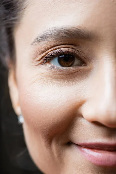 Обрізаний вид усміхненої жінки, що дивиться на камеру, концепція догляду за очима — стокове фото