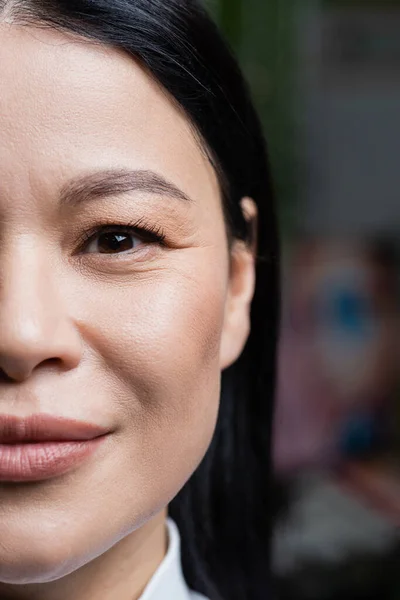 Vue partielle de sourire asiatique femme regardant caméra, concept de soins des yeux — Photo de stock