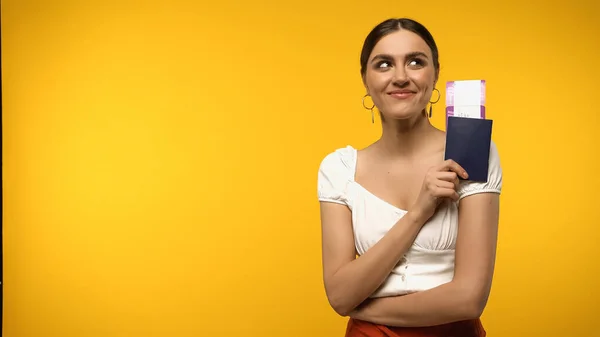 Smiling traveler holding passport and air ticket isolated on yellow — Stock Photo