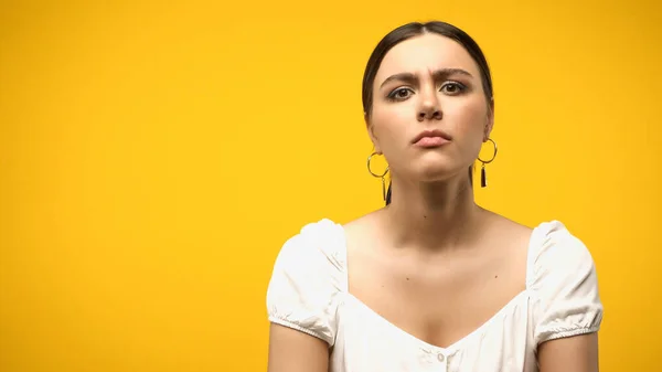 Skeptical woman in blouse and earrings looking at camera isolated on yellow — Photo de stock