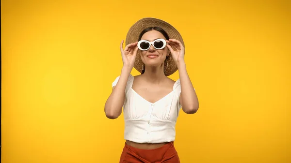 Молода модель в сонячному капелюсі тримає сонцезахисні окуляри ізольовані на жовтому — стокове фото