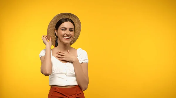 Усміхнена модель в блузці і солом'яному капелюсі дивиться на камеру ізольовано на жовтому — стокове фото