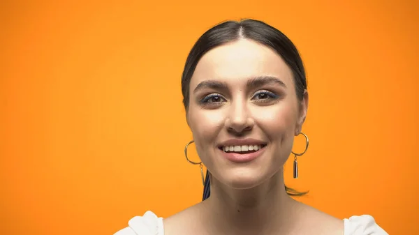 Portrait of smiling woman looking at camera isolated on orange — Photo de stock