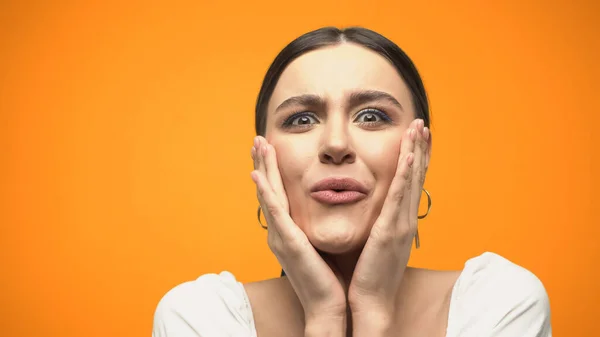 Amazed woman in blouse touching face isolated on orange — Stock Photo