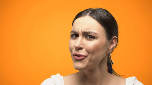 Skeptical brunette woman looking at camera isolated on orange - foto de stock