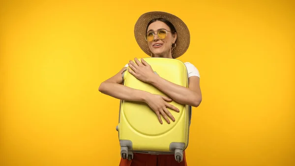 Cheerful tourist holding suitcase isolated on yellow — Photo de stock