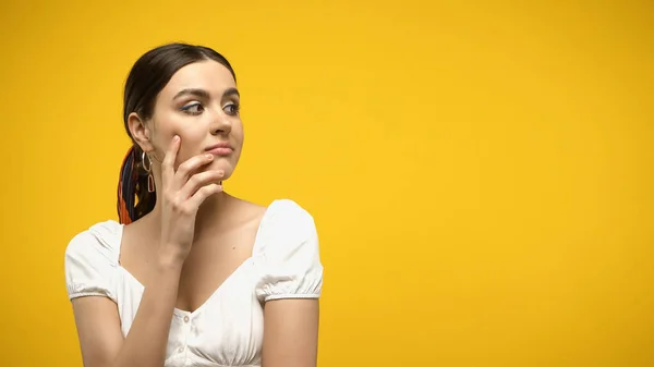 Donna pensierosa in camicetta toccare il viso isolato su giallo — Foto stock