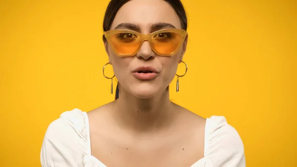 Shocked woman in sunglasses looking at camera isolated on yellow — Stockfoto