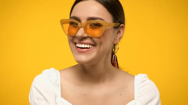 Modèle souriant en lunettes de soleil et chemisier regardant la caméra isolée sur jaune — Photo de stock