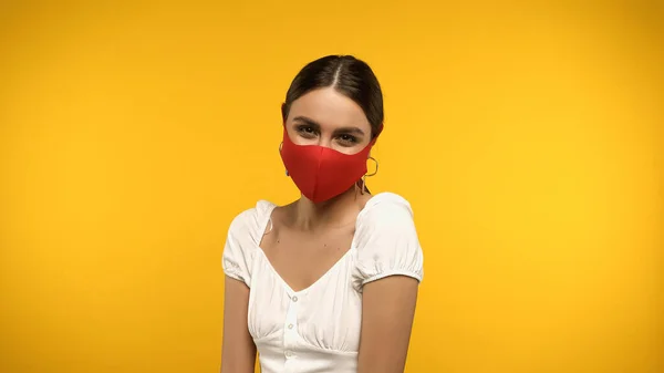 Brunette woman in blouse and protective mask looking at camera isolated on yellow — стоковое фото