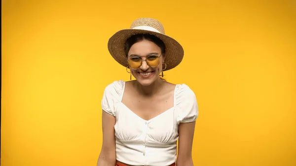 Cheerful woman in straw hat and sunglasses isolated on yellow — стоковое фото