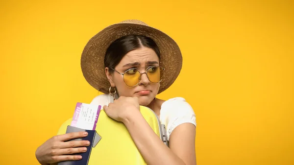 Afraid tourist in sunglasses holding passport, air ticket and suitcase isolated on yellow — Fotografia de Stock