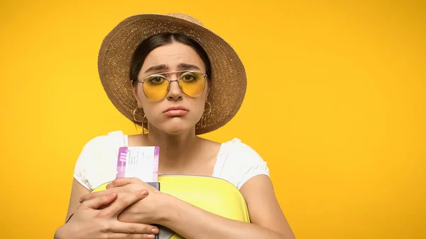 Upset tourist in straw hat holding passport and baggage isolated on yellow — Stock Photo