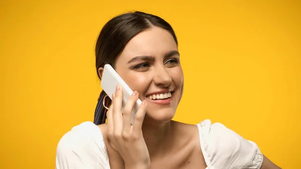 Mulher morena feliz falando no celular isolado no amarelo — Fotografia de Stock