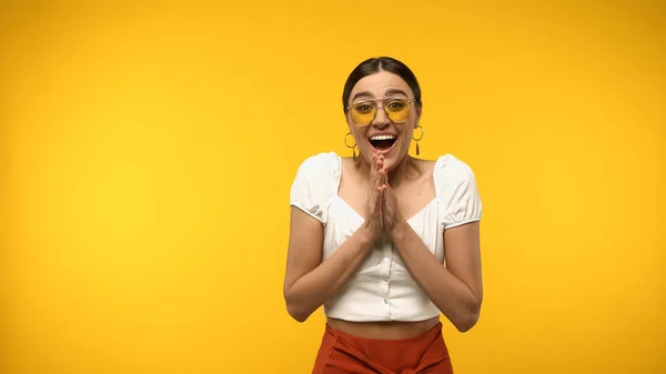 Excited woman in blouse and sunglasses looking at camera isolated on yellow — Foto stock