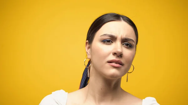 Upset brunette woman looking away isolated on yellow — Stock Photo