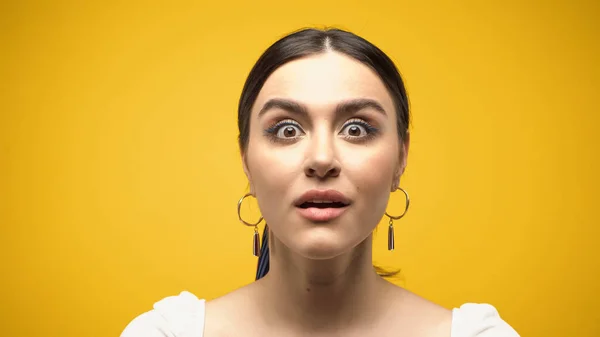 Shocked brunette woman in blouse looking at camera isolated on yellow — Stockfoto