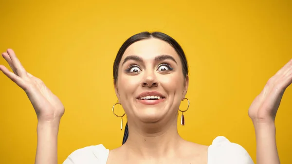 Amazed woman gesturing and looking at camera isolated on yellow — Stock Photo