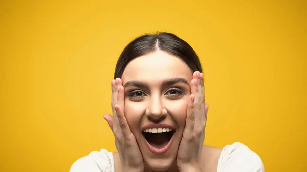 Excited brunette model touching cheeks isolated on yellow — Foto stock