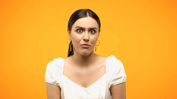 Confused woman in blouse looking at camera isolated on yellow — Foto stock