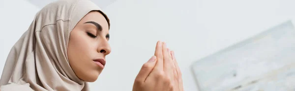 Low angle view of muslim woman in hijab praying at home, banner — Stock Photo