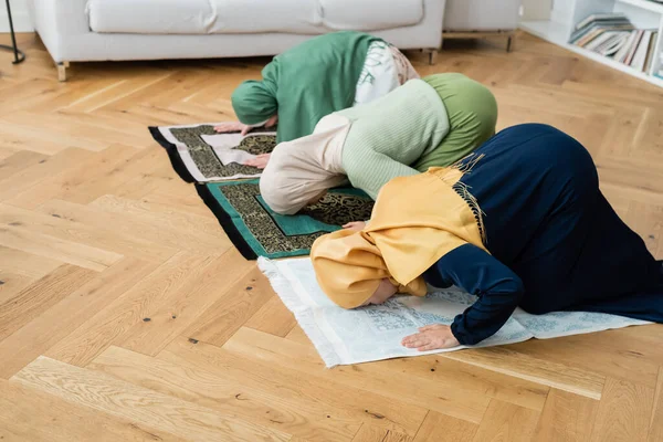 Multiethnische Frauen und Mädchen in Hijabs beugen sich zu Hause auf Lumpen — Stockfoto