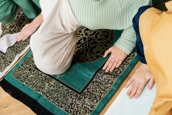 Visão superior de mulheres muçulmanas orando em tapetes tradicionais perto da criança em casa — Fotografia de Stock