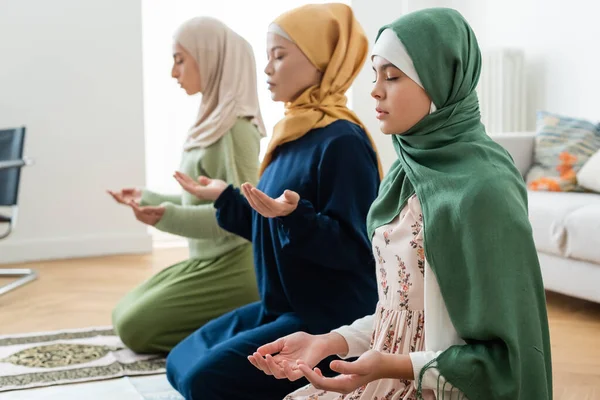 Teenager praying near blurred multiethnic family at home — Stock Photo