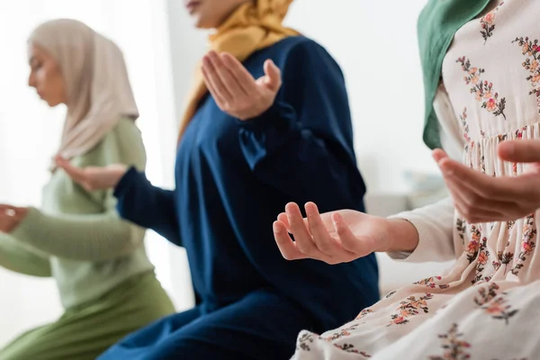 Niño musulmán rezando cerca borrosa mamá y la abuela en casa - foto de stock