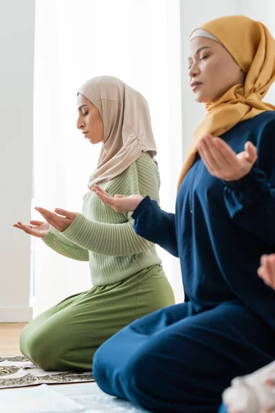Asian mother and young muslim daughter praying at home — Stock Photo