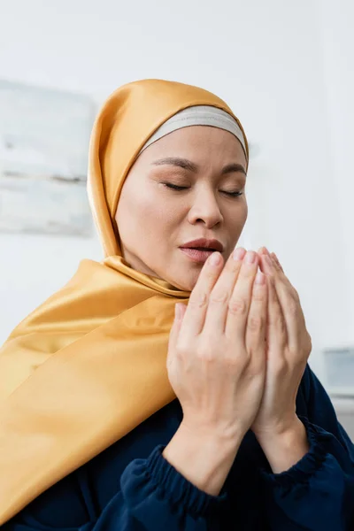 Asian woman in traditional hijab praying at home — Stock Photo