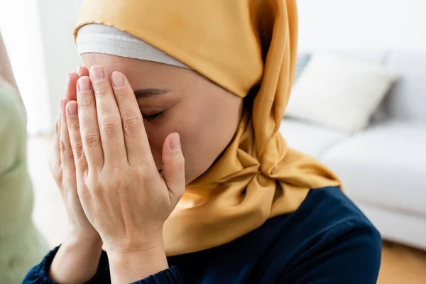 Азиатская женщина покрывает лицо, молясь дома — стоковое фото