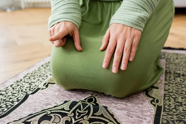 Vista recortada de la mujer musulmana señalando con el dedo mientras reza en casa - foto de stock