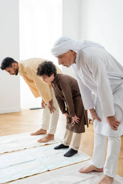 Mature man standing on rug near arabian family at home — Stock Photo