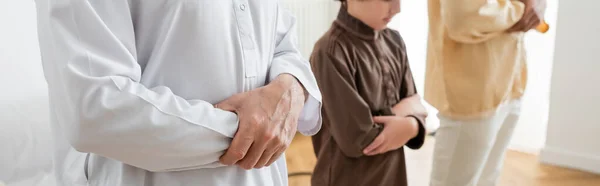 Cropped view of middle aged arabian man praying near grandson and son at home, banner — Stock Photo