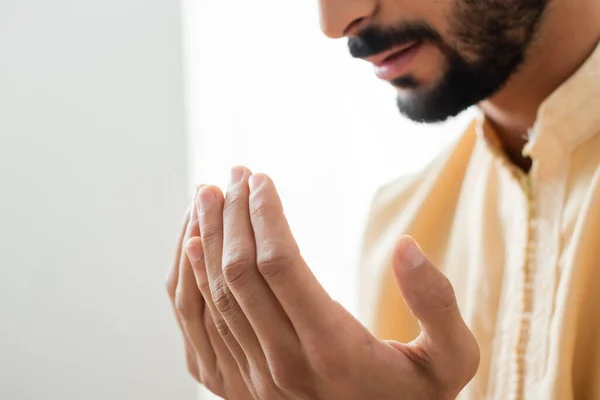Cropped view of hands of blurred arabian man praying at home — Stock Photo