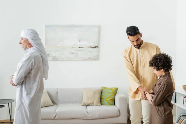 Reifer Mann betet in der Nähe von muslimischen Vater und Sohn zu Hause — Stockfoto