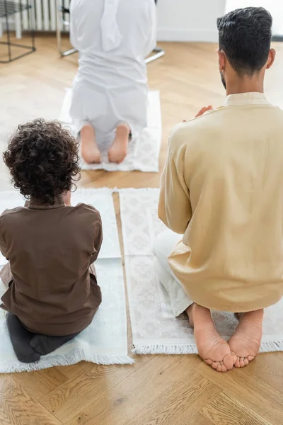 Back view of arabian father and son praying near mature grandfather at home — Stock Photo