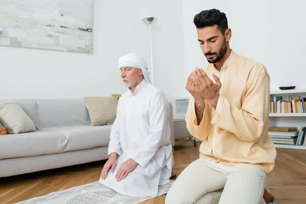 Père d'âge moyen et fils arabe priant à la maison — Photo de stock