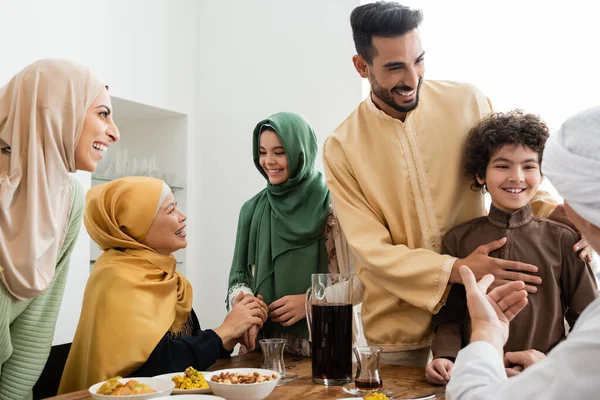 Feliz familia musulmana interracial hablando cerca de la comida en casa - foto de stock