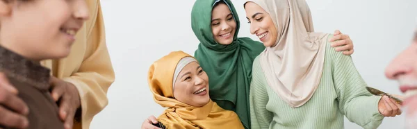 Усміхнена міжрасова мусульманська сім'я обіймається вдома, банер — стокове фото