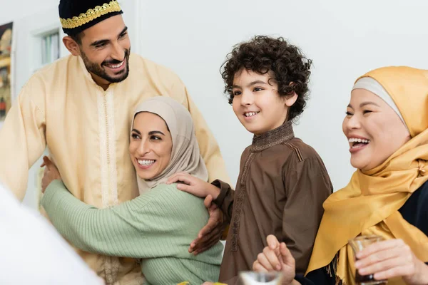 Árabe chico sonriendo cerca feliz musulmán padres y asiático abuela - foto de stock