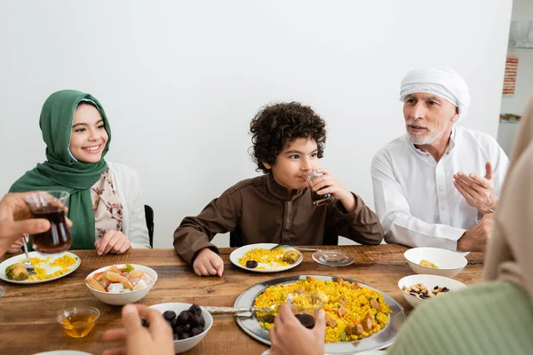 Middle aged muslim man pointing with hand during dinner with interracial grandchildren — Stock Photo