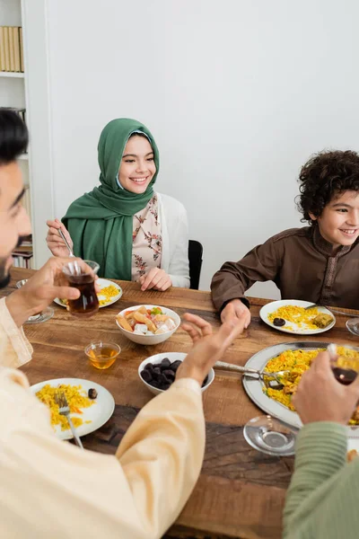 Happy interracial muslim kids having dinner with blurred parents at home — Stock Photo