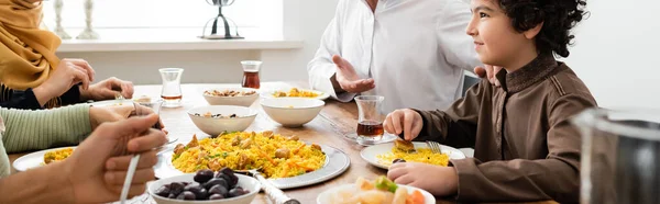 Arabian boy smiling during dinner with muslim family at home, banner — Stock Photo