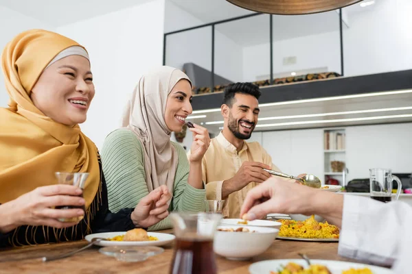 Femme arabe heureuse manger des fruits de date pendant le dîner avec la famille musulmane multiethnique — Photo de stock