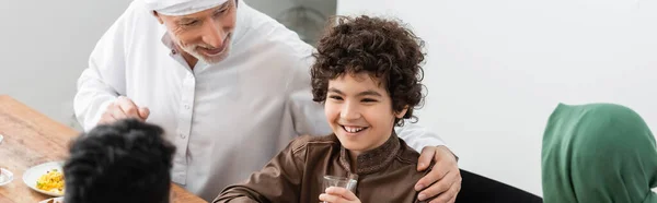 Homme musulman mature étreignant petit-fils arabe pendant le dîner avec la famille, bannière — Photo de stock